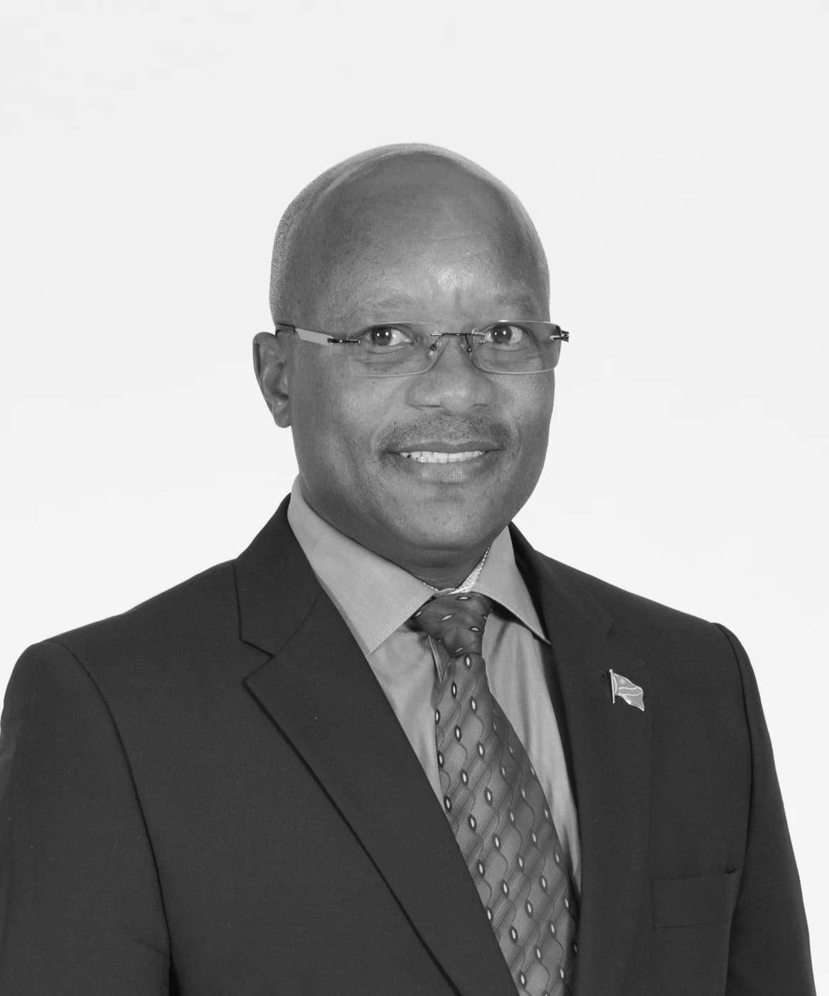 Black and white studio portrait of Bonny V. Idhenga in a dark suit and tie